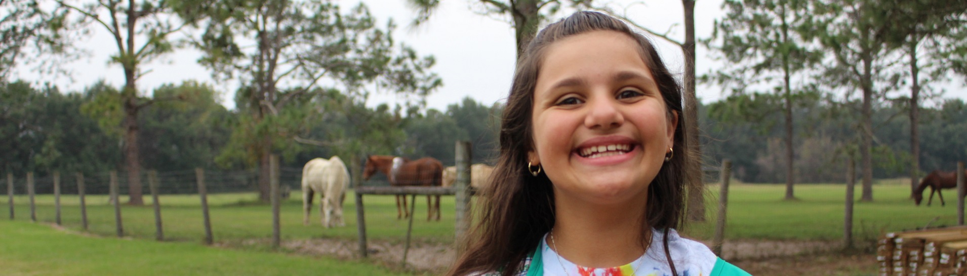  High school girl in Girl Scout sash and winter jacket smiling at camera against green backdrop. 