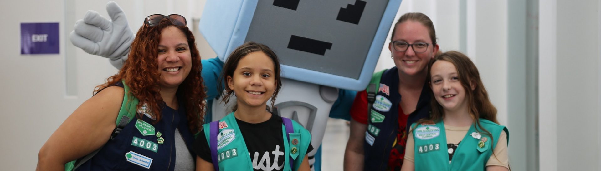 two girl scout juniors outside wearing junior vest uniform smiling and hugging 