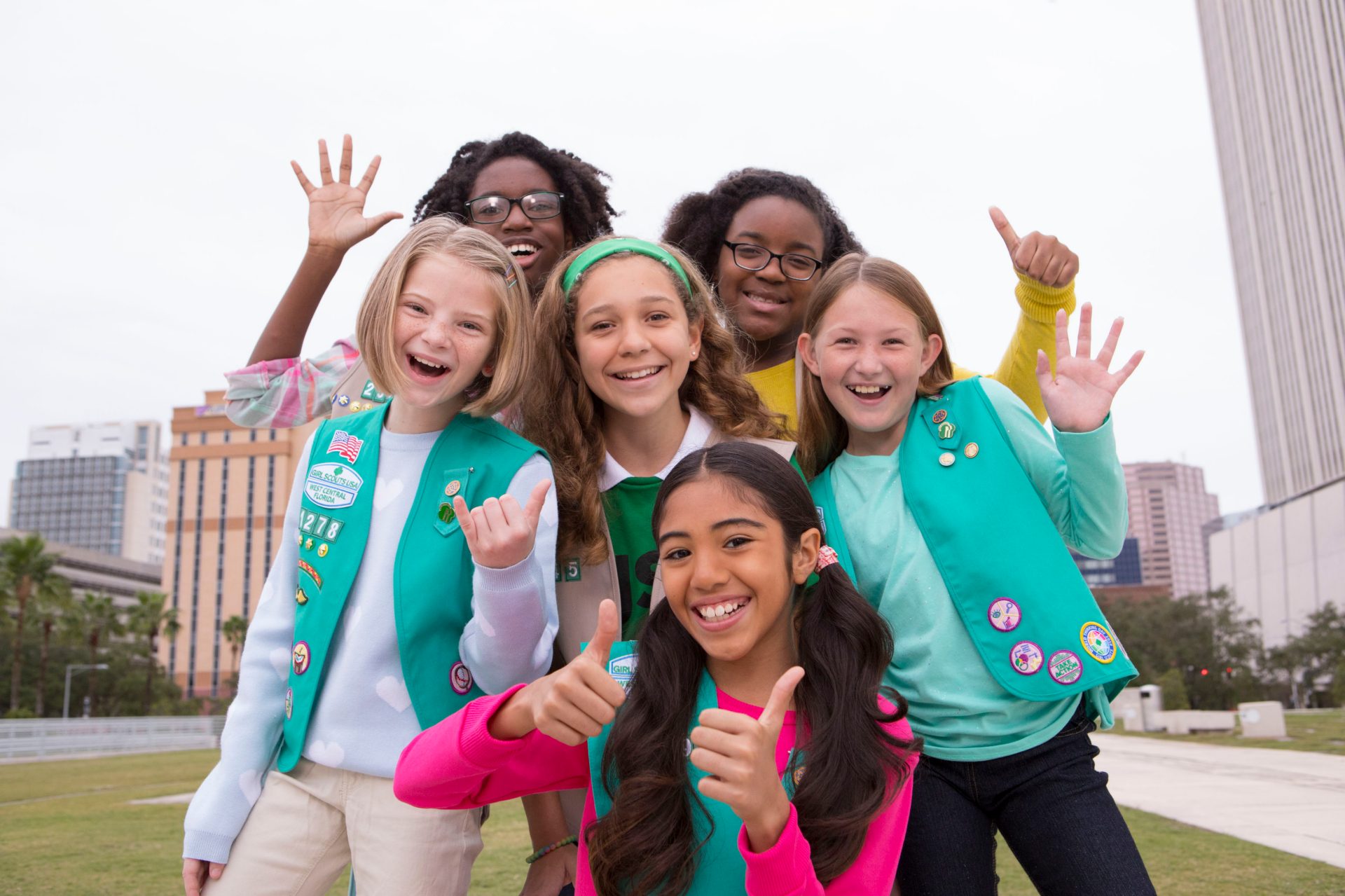 Troop leader with two Girl Scouts smiling outdoors