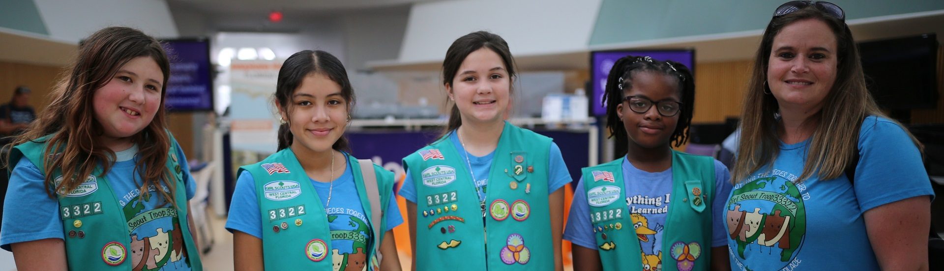  three young girl scouts with their arms wrapped around one another and smiling at the camera 