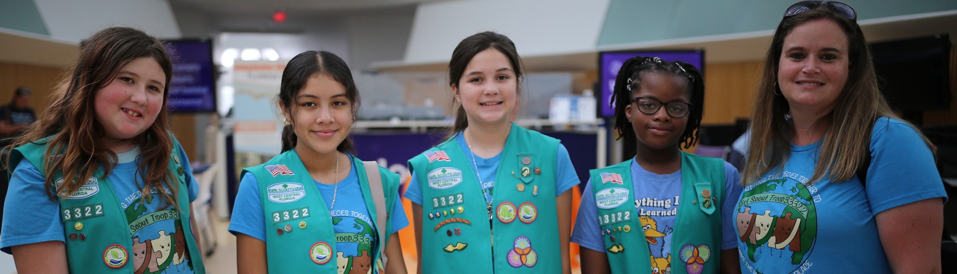  portrait of ambassador girl scout wearing vest and smiling at camera in front of a brick building 