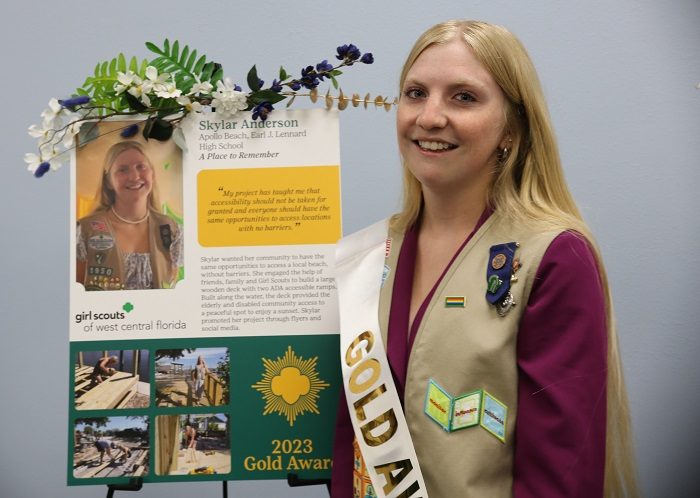 ambassador high school girl scout wearing sash outside against green background